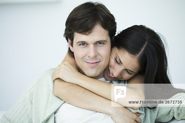 Paar umarmend  Mann lächelt in die Kamera  Frau schaut hinunter