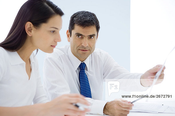 Businessman showing document to female associate