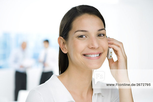 Professional woman using cell phone  smiling at camera