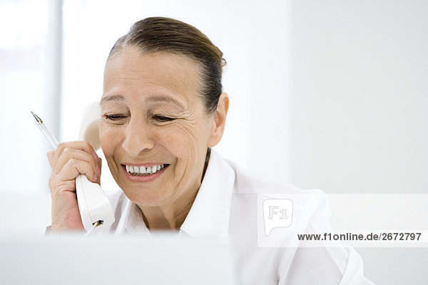 Senior woman using landline phone  smiling