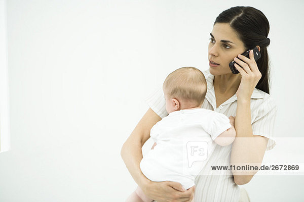 Mother holding infant  using cell phone