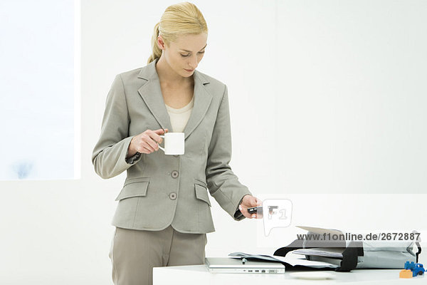 Professionelle Frau mit Kaffeetasse  Blick nach unten  SMS