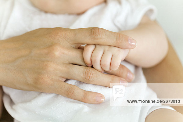 Baby's hand holding adult's finger  close-up