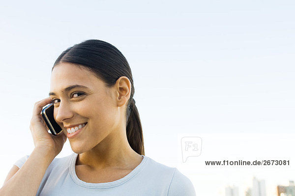 Young woman talking on cell phone  smiling at camera