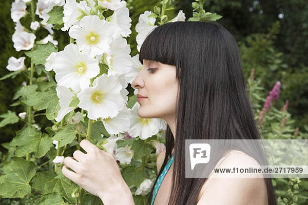 Frau riecht Blumen im Garten