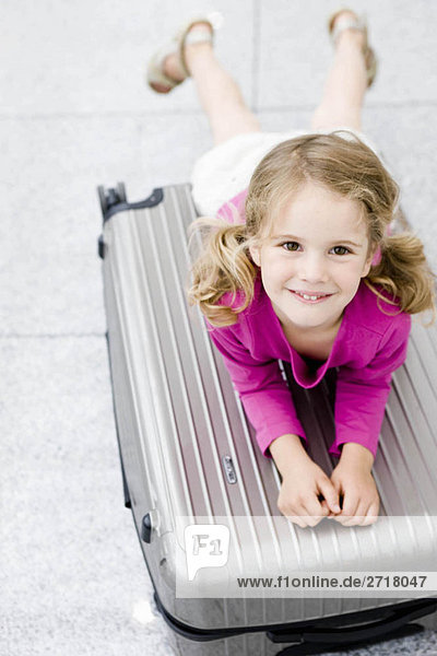 Girl smiling leaning on suitcase
