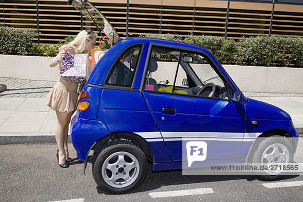 Young woman loading electric car
