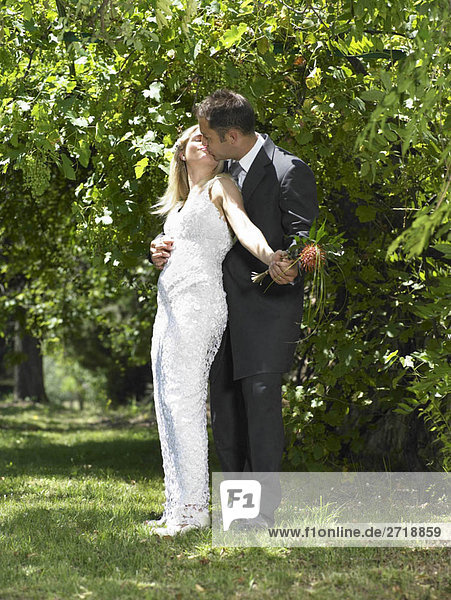 Braut und Bräutigam küssen im Garten