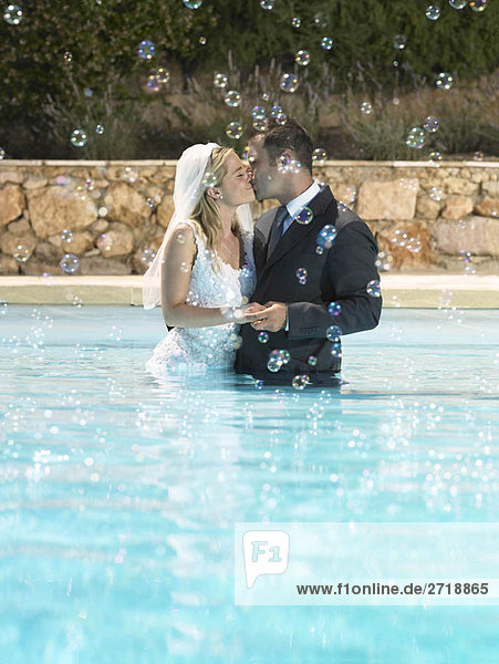 Braut und Bräutigam küssen im Pool