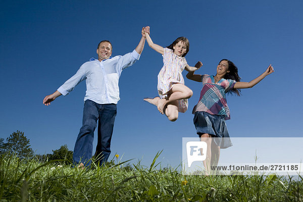 Junge Familie mit Tochter (6-7) beim Spaziergang über die Wiese  Spaß haben