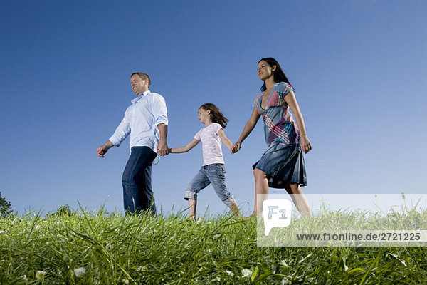 Eltern und Tochter (6-7) beim Spaziergang über die Wiese