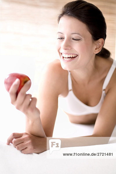 Junge Frau hält einen Apfel  lächelnd