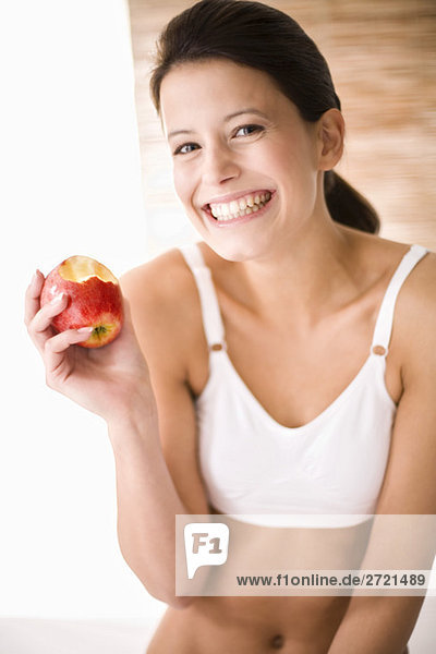 Junge Frau hält Apfel abgebissen  lächelnd