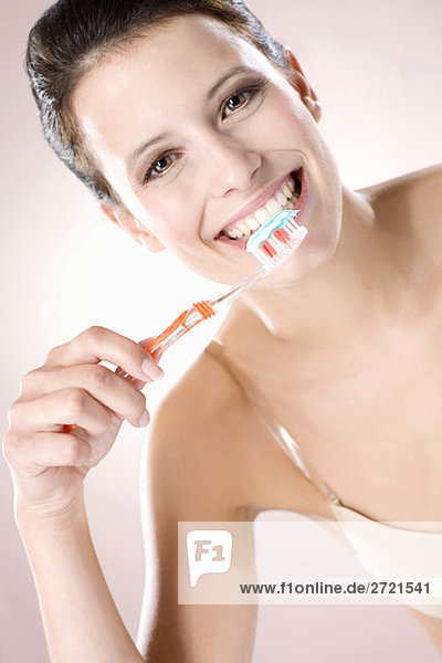 Young woman brushing her teeth  smiling  close up