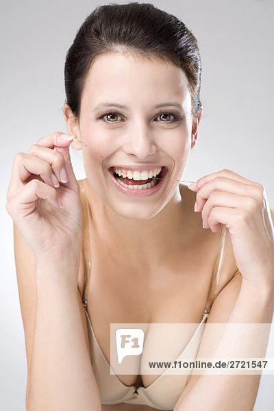 Young woman flossing her teeth  close up