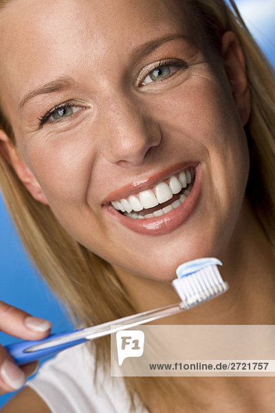 Junge Frau mit Zahnbürste  lächelnd  Portrait