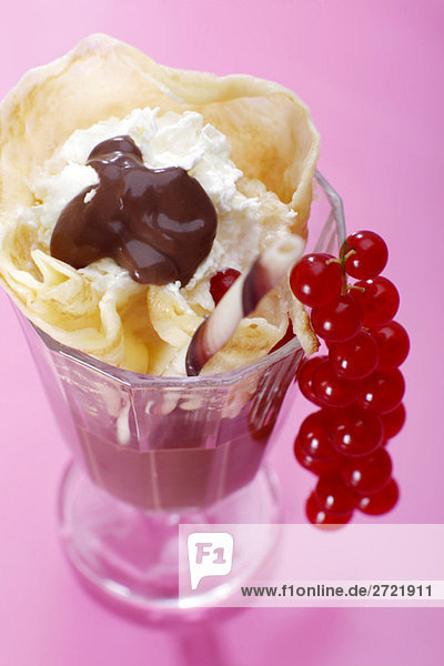 Crepes with whipped cream  chocolate sauce and red currants  close-zo