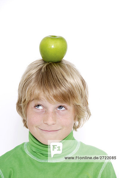 Kleiner Junge (10-11) balanciert Apfel auf Kopf