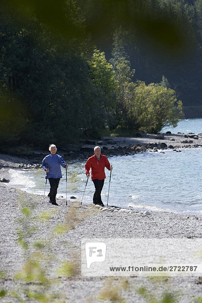 Deutschland  Bayern  Walchensee  Seniorenpaar  Nordic Walking am Seeufer
