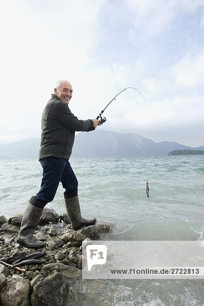 Senior Mann  der im See fischt.