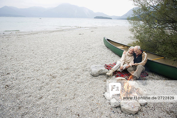 Germany  Bavaria  Walchensee  Senior couple sitting at campfire