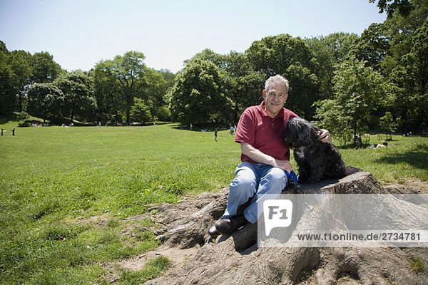 A man sitting with his dog in a park  Prospect Park  Brooklyn  New York  USA