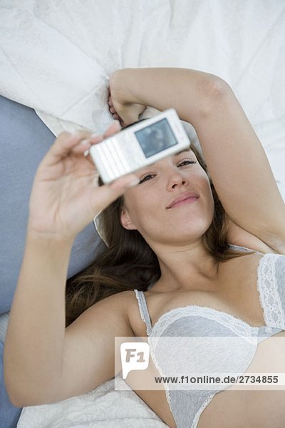 A woman lying down and taking a photograph of herself