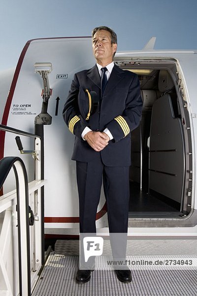 A pilot standing in front of the doorway of a plane
