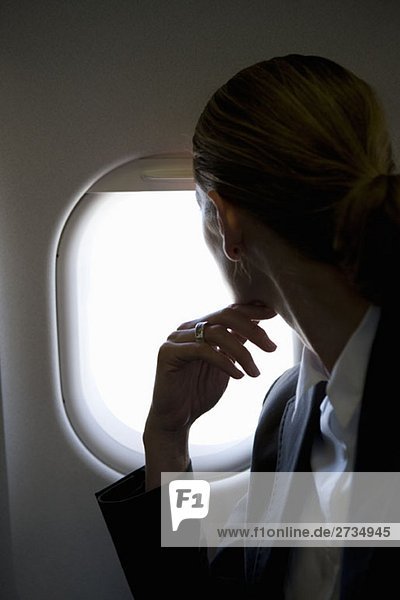 Eine Passagierin  die durch ein Fenster in einem Flugzeug schaut.