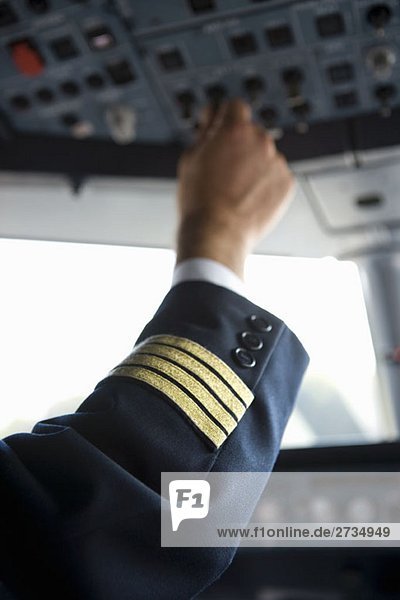 Die Hand eines Piloten über das Bedienfeld im Cockpit eines Verkehrsflugzeuges