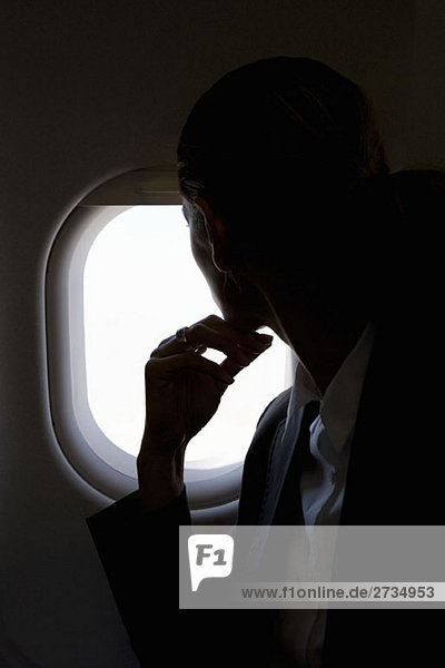 Eine Passagierin  die durch ein Fenster in einem Flugzeug schaut.