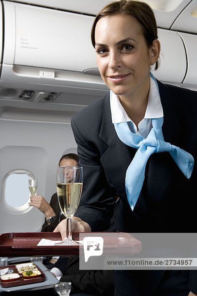 Eine Flugbegleiterin  die Champagner serviert.