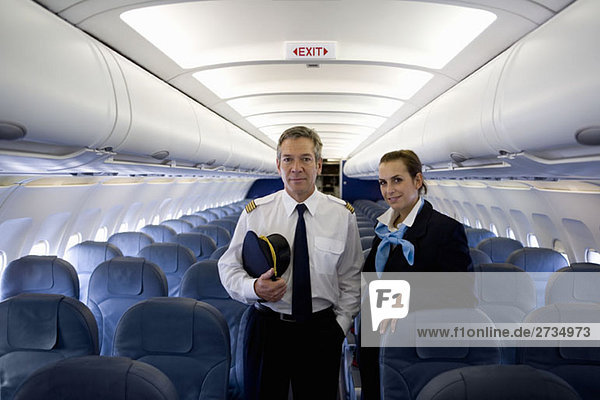 A pilot and a flight attendant standing in the cabin of a plane