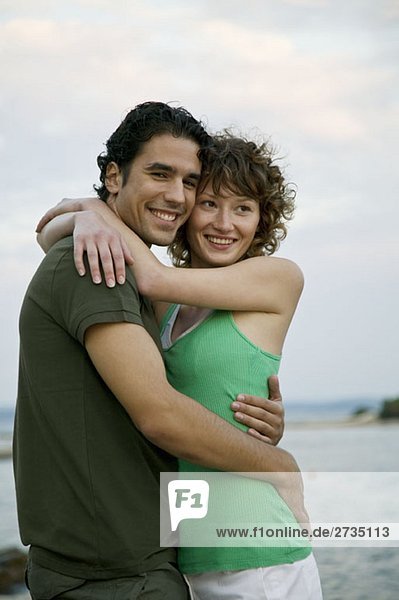 Ein junges Paar  das sich am Meer umarmt.