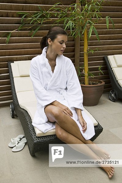 Eine Frau im Bademantel sitzt am Rand eines Sessels