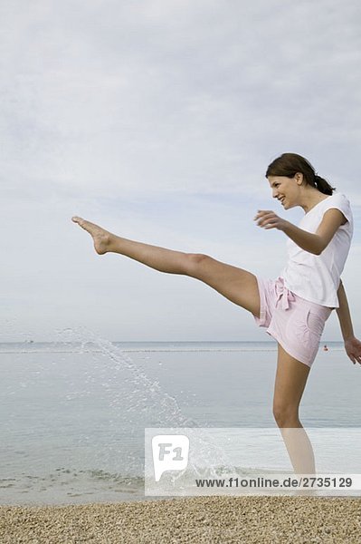 Eine Frau  die mit dem Fuß ins Wasser tritt.