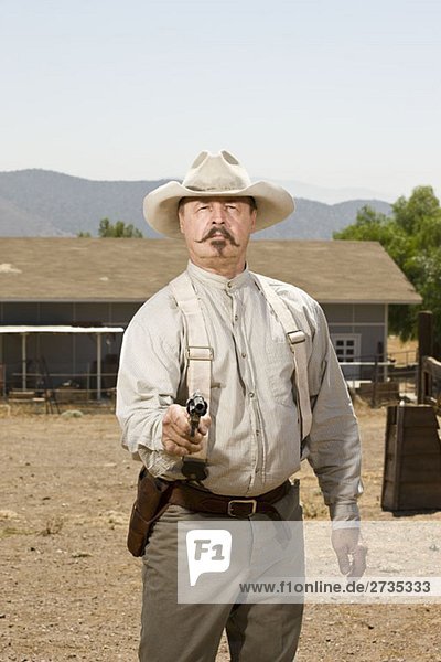 Porträt eines Cowboys  der auf seine Waffe zielt.