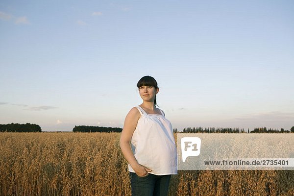 A pregnant woman standing near a wheat field