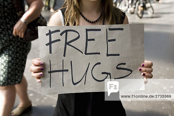 A young woman holding a sign saying Free Hugs
