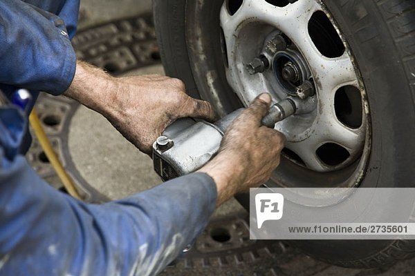 A car mechanic unscrewing a wheel