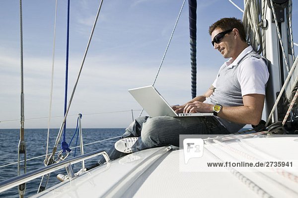 Ein Mann  der einen Laptop auf einer Yacht benutzt.