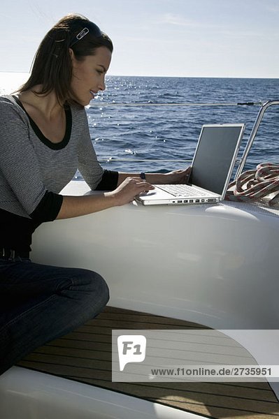 Eine Frau  die einen Laptop auf einer Yacht benutzt.