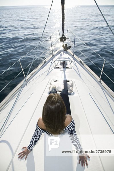 A woman sitting on the bow of a yacht
