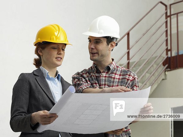 Ein Architekt im Gespräch mit einem Bauarbeiter auf einer Baustelle