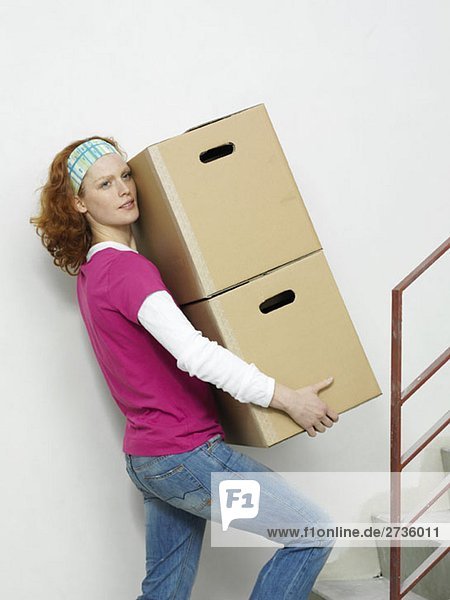 Eine Frau trägt Kisten die Treppe hinauf.