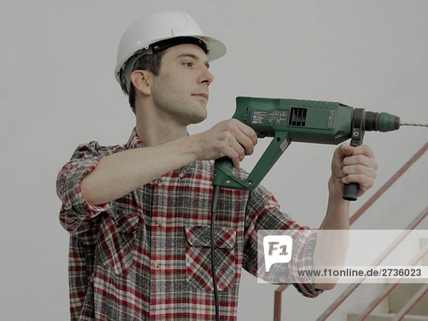 A construction worker using a drill on a wall
