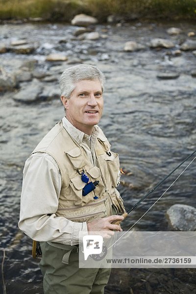 A man standing in a river and holding a fly rod