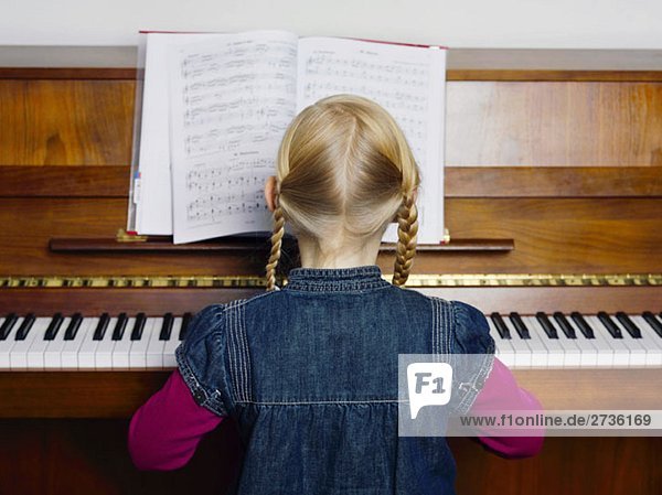 A little girl playing a piano  rear view  portrait