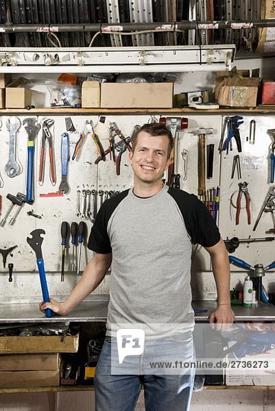 Ein Mann mit einem Schraubenschlüssel in einer Werkstatt.