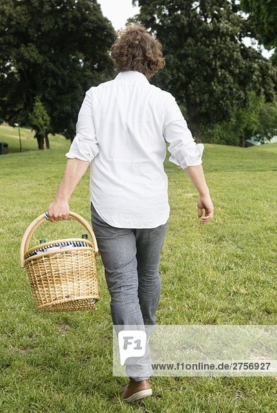 Man from behind carrying picnic basket